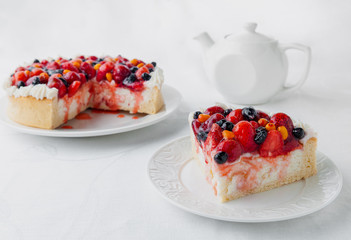 A piece of homemade curd berry pie. Garnished with cream and berries of strawberries, blueberries and sea buckthorn. On a white plate. Close-up. White background. 