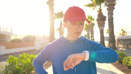 Woman stops while jogging to check the data in the smart watch application, rests and continues to run