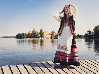 Beautiful girl in national dress in an ancient medieval castle in Trakai in Lithuania. Retro photography. Restoring the atmosphere of the Middle Ages. - obrazy, fototapety, plakaty