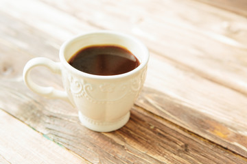 A cup of hot coffee on a folded white cloth and an old wooden table