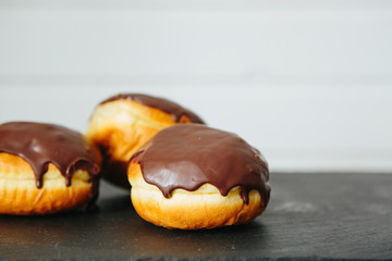 Donut with white glaze and chocolate crumbs, donut with chocolate glaze on light wooden table