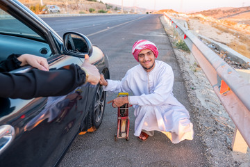 Arabic fixing his car flat tire