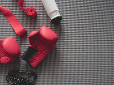 top view of boxing gym concept with boxing glove, Gym Outfit, skipping rope and accessories on yoga mat background.