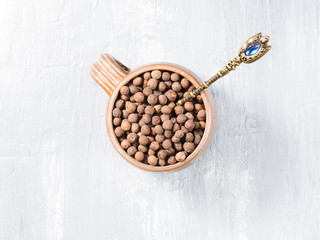 Allspice (Jamaica pepper) in a clay cup and spoon on a gray background