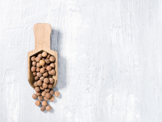 Allspice (Jamaica pepper) on a wooden scoop on a gray background vertically