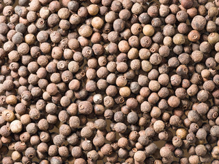 Allspice (Jamaica pepper) on a brown wooden background