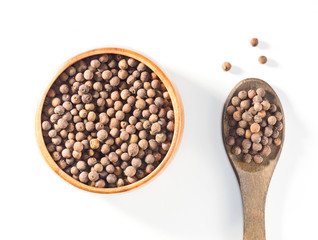 Allspice (Jamaica pepper) in the wooden cup and spoon vertically on white background