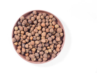 Allspice (Jamaica pepper) in the clay plate on white background