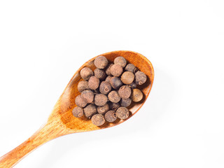 Allspice (Jamaica pepper) in the wooden spoon diagonally on white background