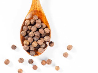 Allspice (Jamaica pepper) in the wooden spoon vertically on white background