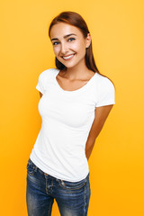Young beautiful woman in a white t-shirt posing on a yellow background