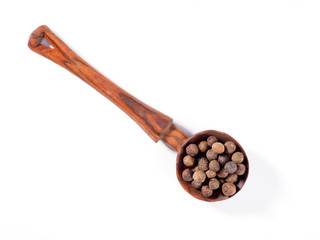 Allspice (Jamaica pepper) in wooden spoon diagonally on white background