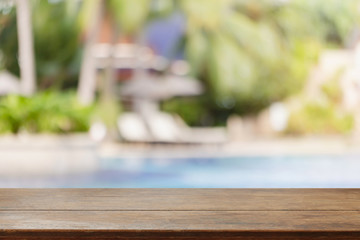 Empty wood table top and blurred swimming pool in tropical resort in summer background - can used for display or montage your products.