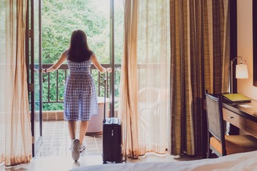 Asian women are staying in a hotel room with luggage.Open the curtain and  door in the room looking...