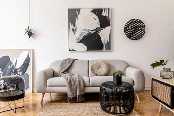 Stylish and scandinavian living room interior of modern apartment with gray sofa, pillows, plaid, plants, design wooden commode, black table, lamp, abstrac paintings on the wall.  Modern home decor. - obrazy, fototapety, plakaty