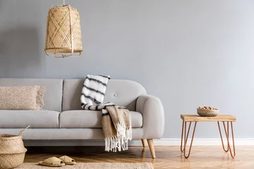 Fotobehang Boho Stylish and design home interior of living room with gray sofa, wooden coffee table , pillows, blankets, rattan lamp, slippers  basket and elegant accessories. Stylish home decor. Template.   © FollowTheFlow