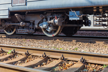 Wheels of a railway train. In the foreground the rails of the oncoming track