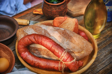 Rustic table with homemade sausage and bread. The food in vintage style, wooden table on the street.