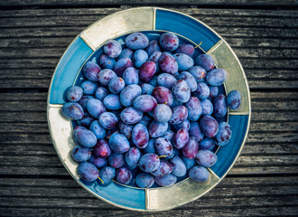 leckere, saftige, reife Zwetschgen, Pflaumen in einer Schale auf einem Holztisch. Selektive Schärfe