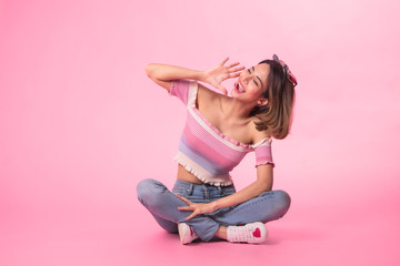 Obraz na płótnie Canvas Thinking asian woman sitting on floor isolated on pink colour background.Asian female model smiling looking up.woman pointing fingers away while sitting on a floor isolated.