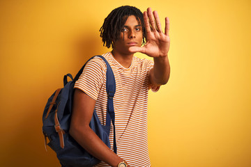 Afro american student man with dreadlocks wearing backpack over isolated yellow background with...