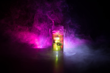 Cocktail glass splashing on dark toned smoky background or colorful cocktail in glass. Party club...