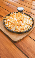 Cheese Fries Plate with white dip served on a wooden outdoor restaurant table