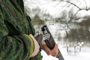 Fototapeta premium Male hunter in camouflage opened hunting rifle. Open double-barreled hunting rifle. Empty trunks without cartridges close-up.