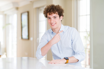 Fototapeta na wymiar Young business man with curly read head cheerful with a smile on face pointing with hand and finger up to the side with happy and natural expression