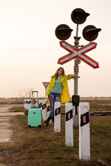 young girl with a suitcase stands on the platform. A girl in a yellow raincoat travels. Autumn...