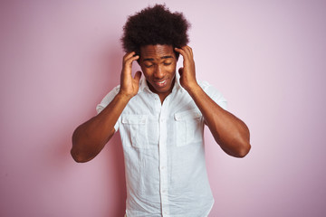 Young american man with afro hair wearing white shirt standing over isolated pink background with hand on head for pain in head because stress. Suffering migraine.