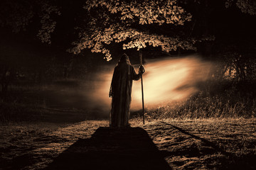 Death with a scythe in the dark misty forest. Woman horror ghost holding reaper in forest