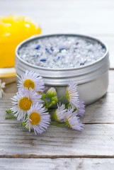 Obraz na płótnie Canvas yellow calendula cream in glass pot, moisturizer and bath salt with white herbal flowers on weathered rusty wooden table background