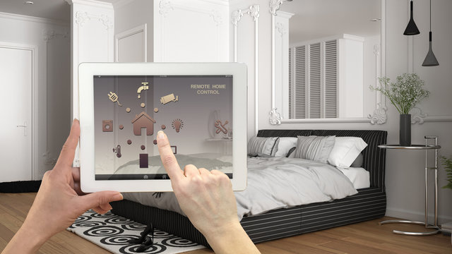 Smart remote home control system on a digital tablet. Device with app icons. Classic luxury bright bedroom in the background, white and gray architecture interior design
