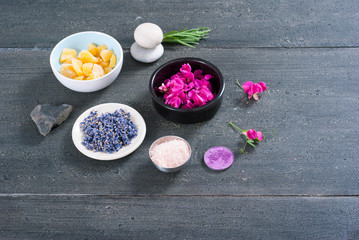 pink linaria flowers and bath salt, dried lavender buds on black wood table