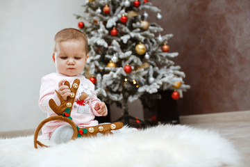 Happy child with deer horns near a Christmas tree.