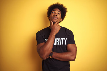 American safeguard man with afro hair wearing security uniform over isolated yellow background with...