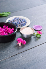 Obraz na płótnie Canvas pink linaria flowers and bath salt, dried lavender buds on black wood table