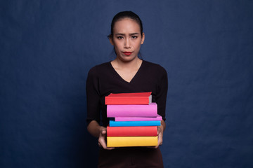 Unhappy young Asian woman studying  with may books.