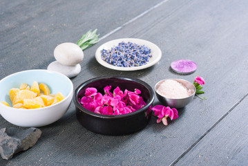 Obraz na płótnie Canvas pink linaria flowers and bath salt, dried lavender buds on black wood table