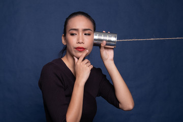 Obraz premium Surprised young Asian woman with tin can phone.