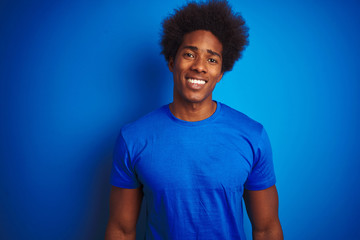 African american man with afro hair wearing t-shirt standing over isolated blue background with a...