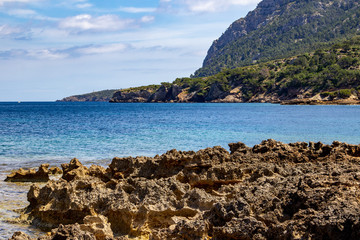 Bucht auf der Halbinsel La Victoria, Mallorca mit Bergr&uuml;cken im Hitergrund, Segelyacht und Felsen im Meer