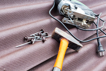Close up view on asphalt roofing shingles background with hammer and nails.