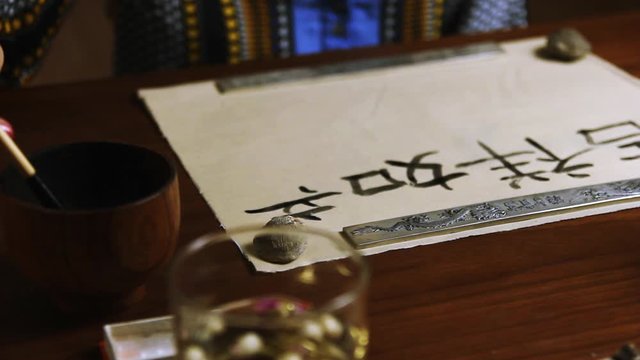 Girl writes Chinese characters (Translation from Chinese Mandarin 1: jixiang ruyi wanshi ankang- to be gratified propitiously with everything in good health, 2: fugui jixiang: wealthy and propitious)