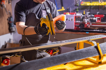 Close up of young man repairing the ski in the service