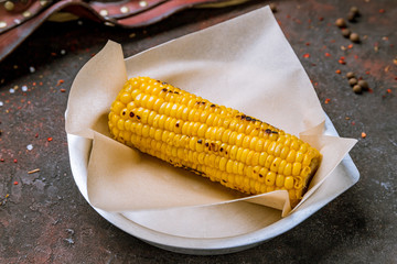 Baked corn on a plate on dark concrete rustic table