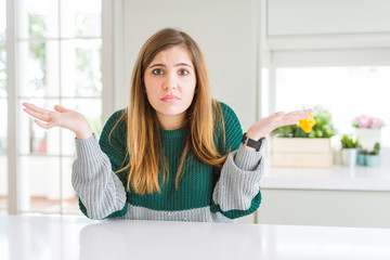 Young beautiful plus size woman wearing casual striped sweater clueless and confused expression...