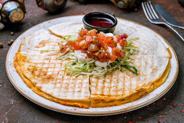 Quesadilla with chicken and sauces on dark concrete rustic table