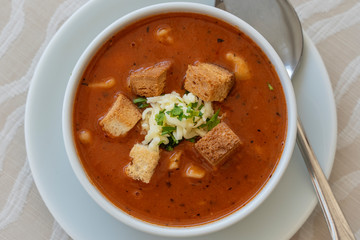 Tomato soup with croutons, cheese and fresh parsley, closeup